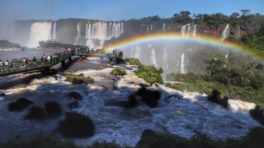 Imagem das Cataratas do Iguaçu, em Foz do Iguaçu, com um arco-íris e céu azul