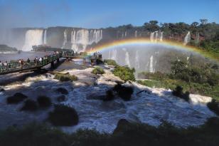 Imagem das Cataratas do Iguaçu, em Foz do Iguaçu, com um arco-íris e céu azul